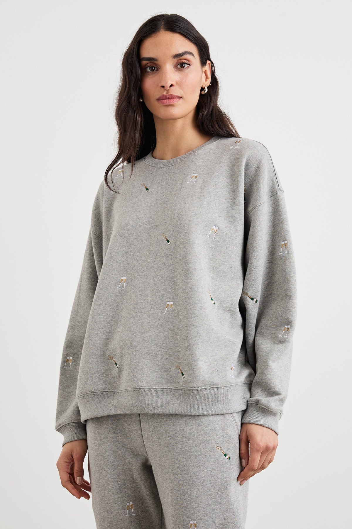 The Varsity Sweatshirt with a Crew Neck and embroidered Champagne Glasses in Champagne Embroidery Colorway, on light grey - Front View Featured on Model 