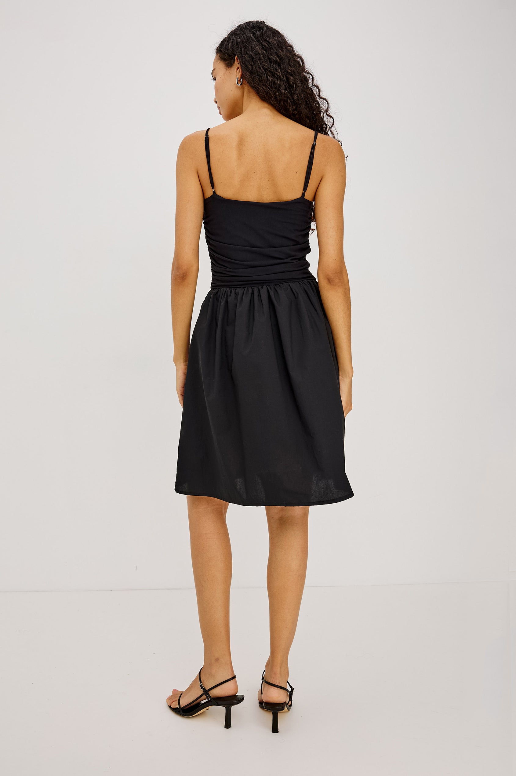 Vienne Mini Dress With Ruched Jersey Fitted Bodice, Full Cotton Poplin Skirt, and Side Pockets in Black Colorway - Full Body Back View Featured on Model