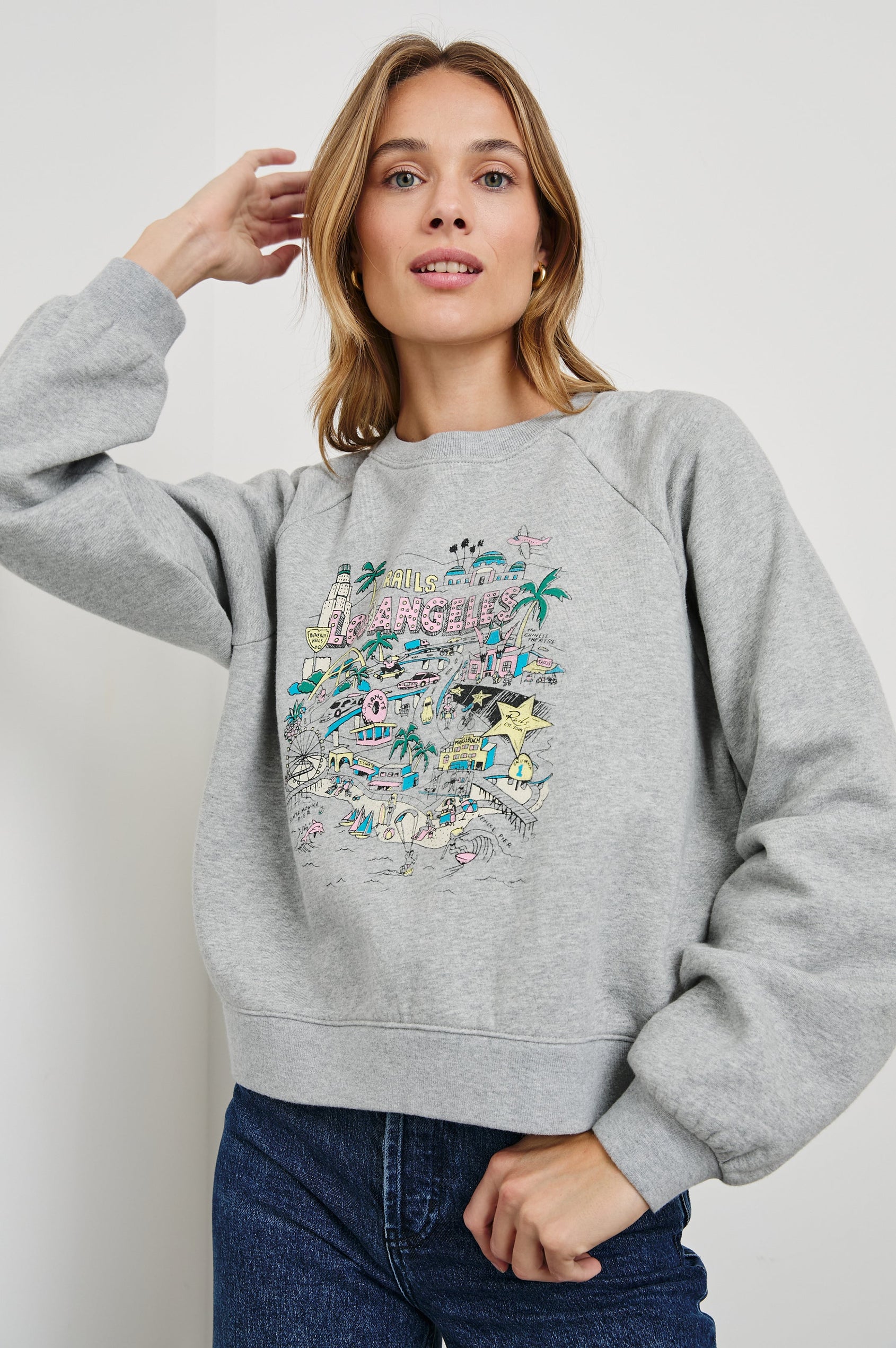 Vintage Raglan Long-Sleeve Sweatshirt with a Crew Neck, an image of landmarks in Los Angeles and the Text, Rails Los Angeles in Rails Los Angeles Map Grey Colorway, Mostly Pink, Yellow and Blue on Grey - Front View Featured on Model