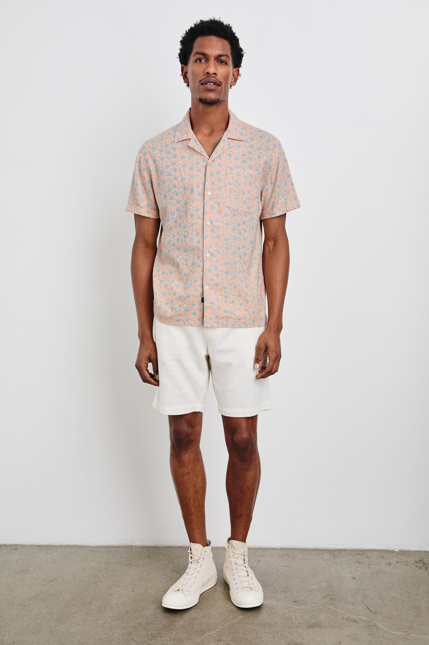 Waimea Short-Sleeve Button Up with a Chest Patch Pocket in Floral Batik Blossom Colorway, blue flowers on peach - Front Full Body View Featured on Model