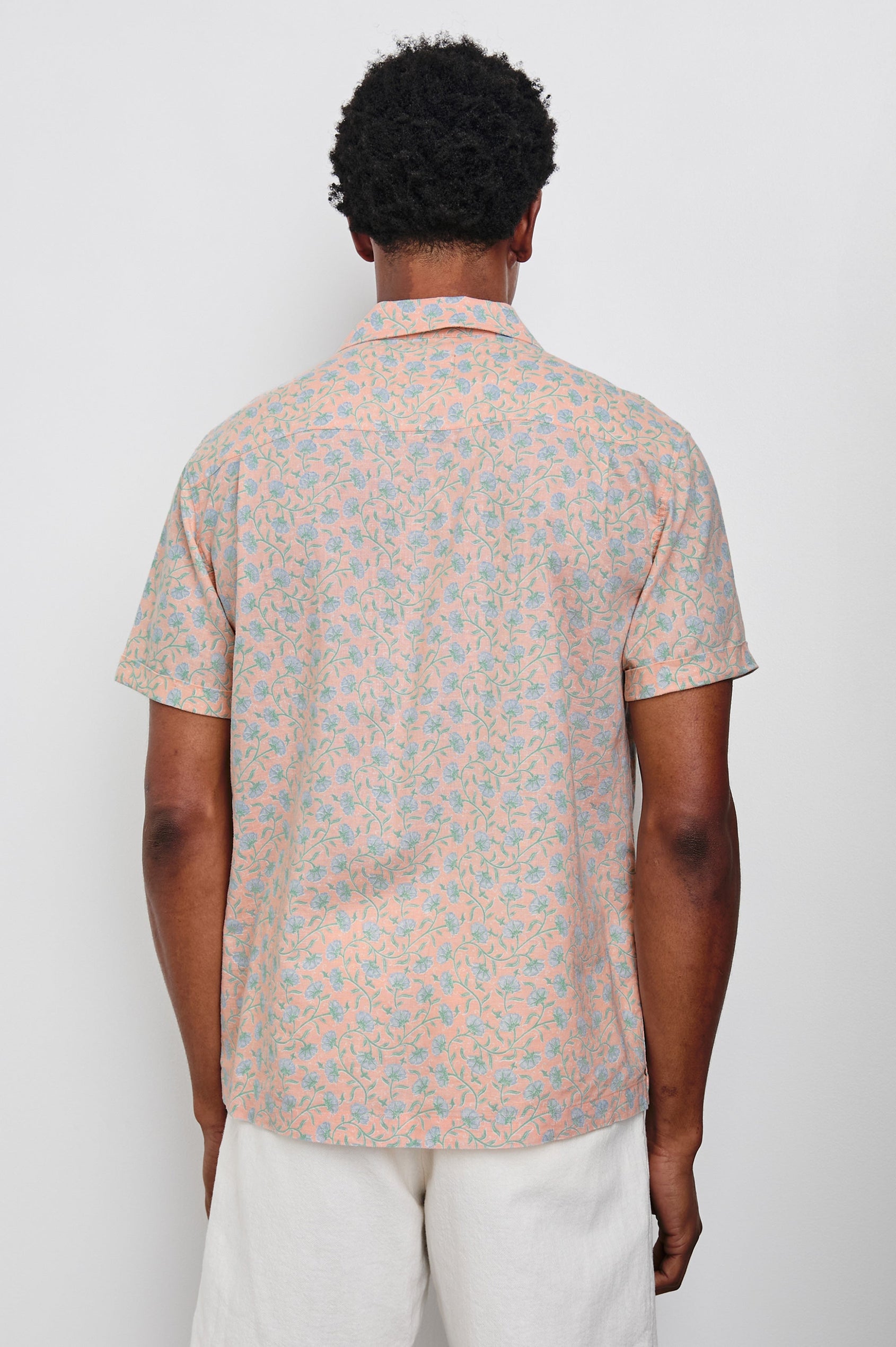 Waimea Short-Sleeve Button Up with a Chest Patch Pocket in Floral Batik Blossom Colorway, blue flowers on peach - Back View Featured on Model