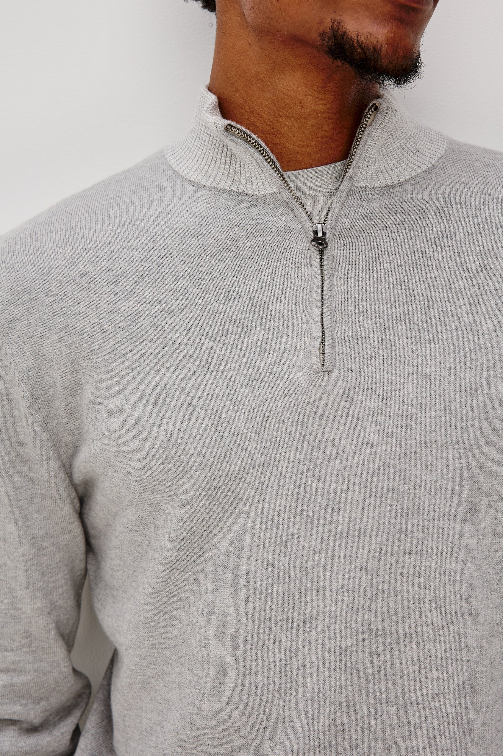 The Waylon is a quarter zip mock neck sweater with long sleeves and rib trim in Grey Heather colorway. Front detail view featured on model.