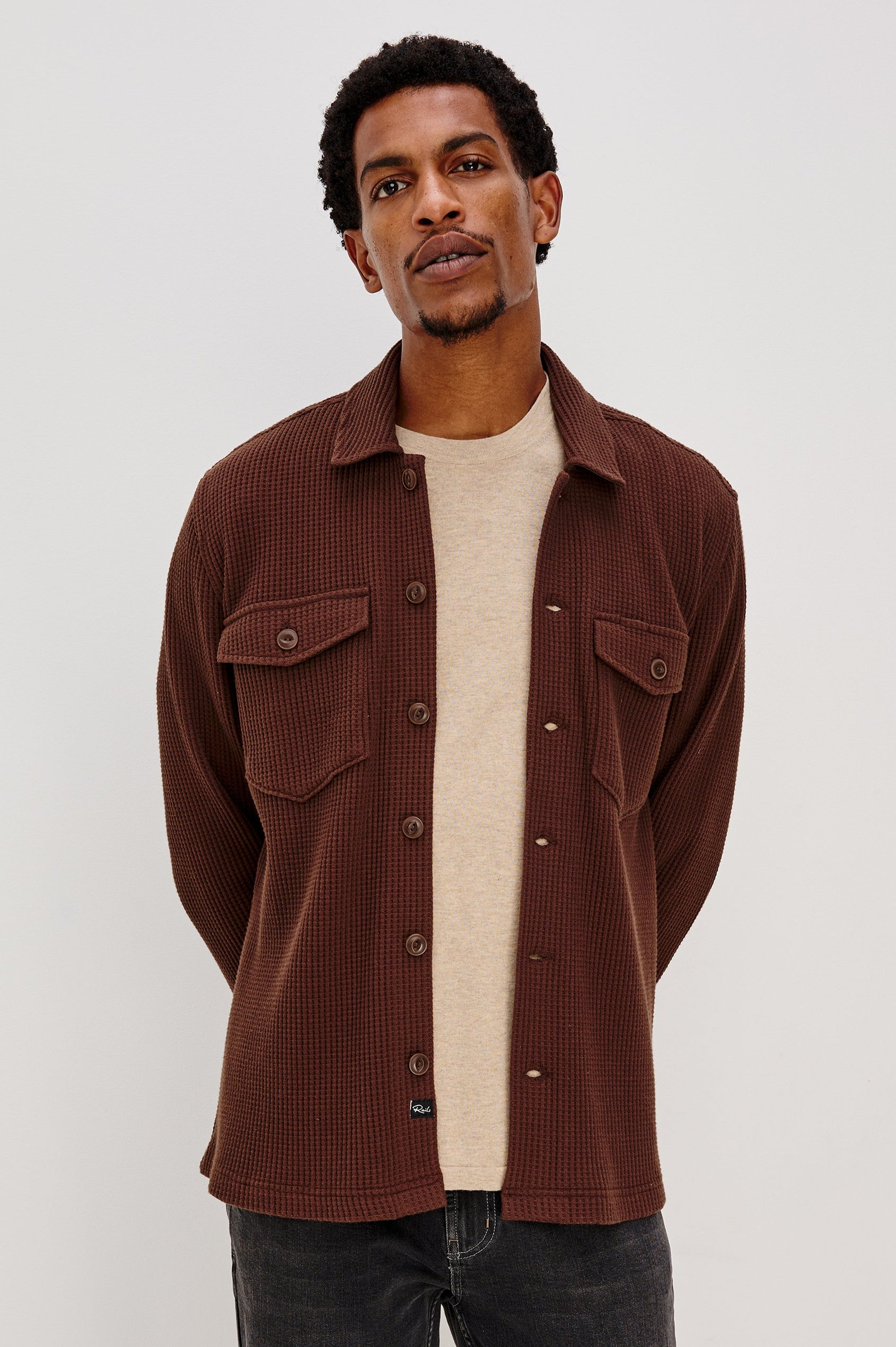 The Wells is a collared button front shirt jacket with contrast brown buttons and two chest pockets in Barley colorway. Front view featured on model.