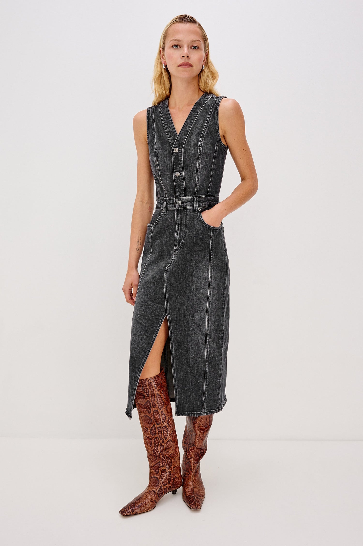 Westwood Sleeveless Denim Midi Dress with Belt Loops, a Button and Zipper Closure for the Skirt and Button Closure on the Bodice, a V neck, a Front Center Thigh Slit, Two Front Pockets  and Two Back Patch Pockets in Black Pearl Colorway, a washed black- Front Full Body View Featured on Model