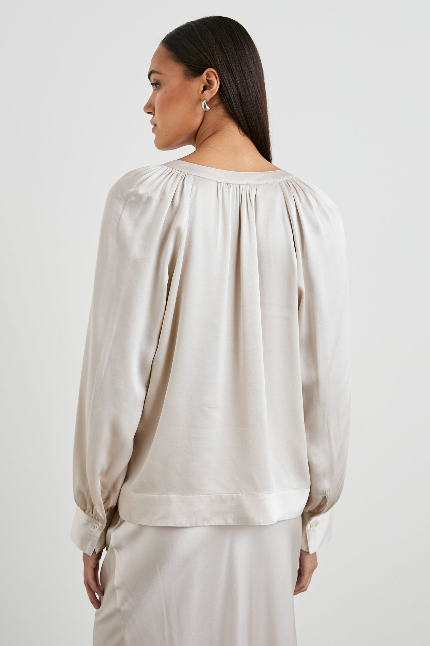 Wynna Long-Sleeve Top with a Deep V Neck and Ruching above the Cuffs and at the Neckline in Ivory Colorway - Back View Featured on Model