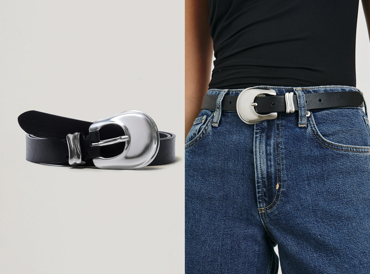 A black leather belt with a large silver-tone buckle, shown both as a standalone product on a light gray background and worn around a model's waist with blue jeans and a black top.