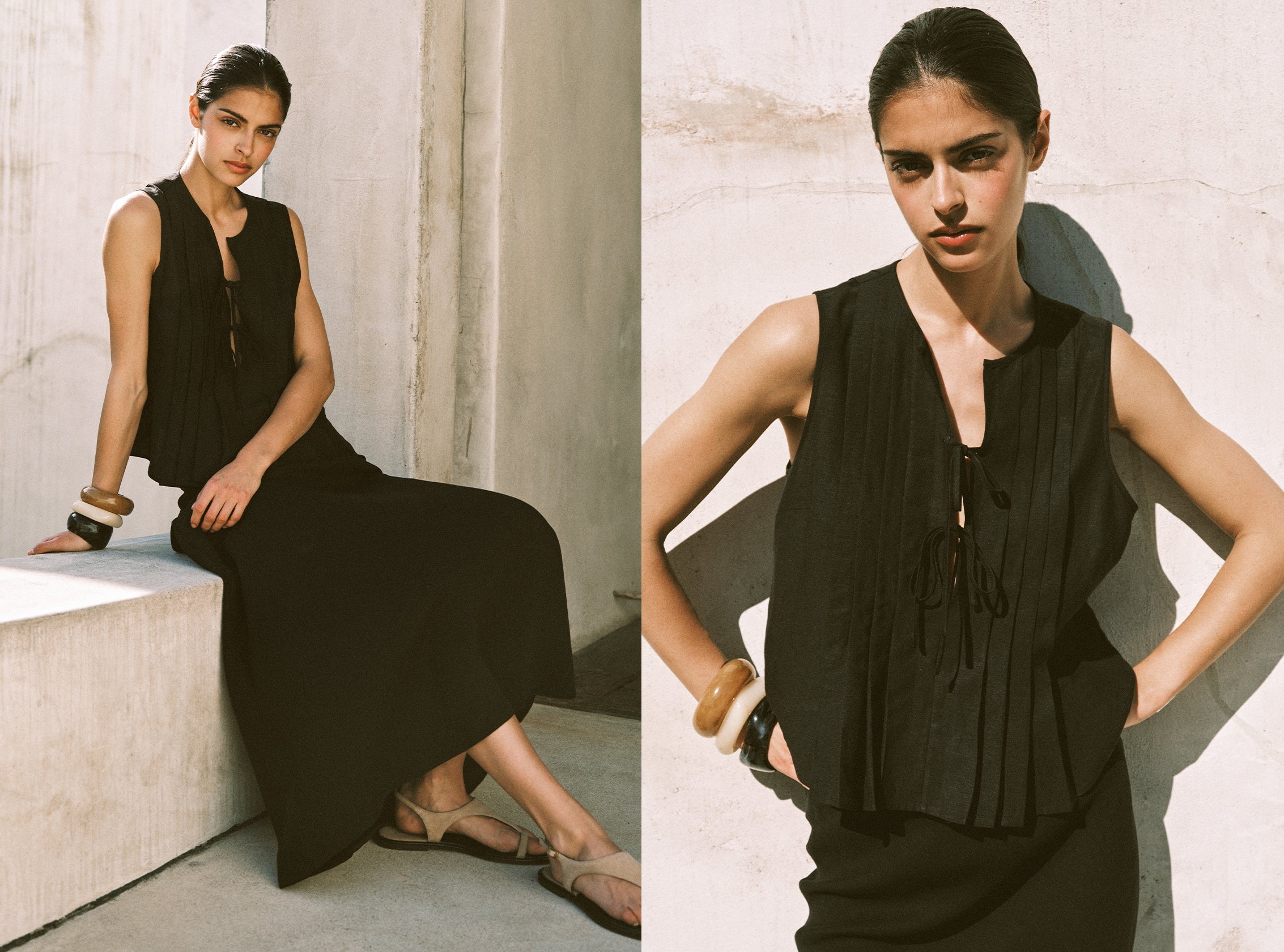 Woman wearing a black sleeveless dress sitting on a stone bench.