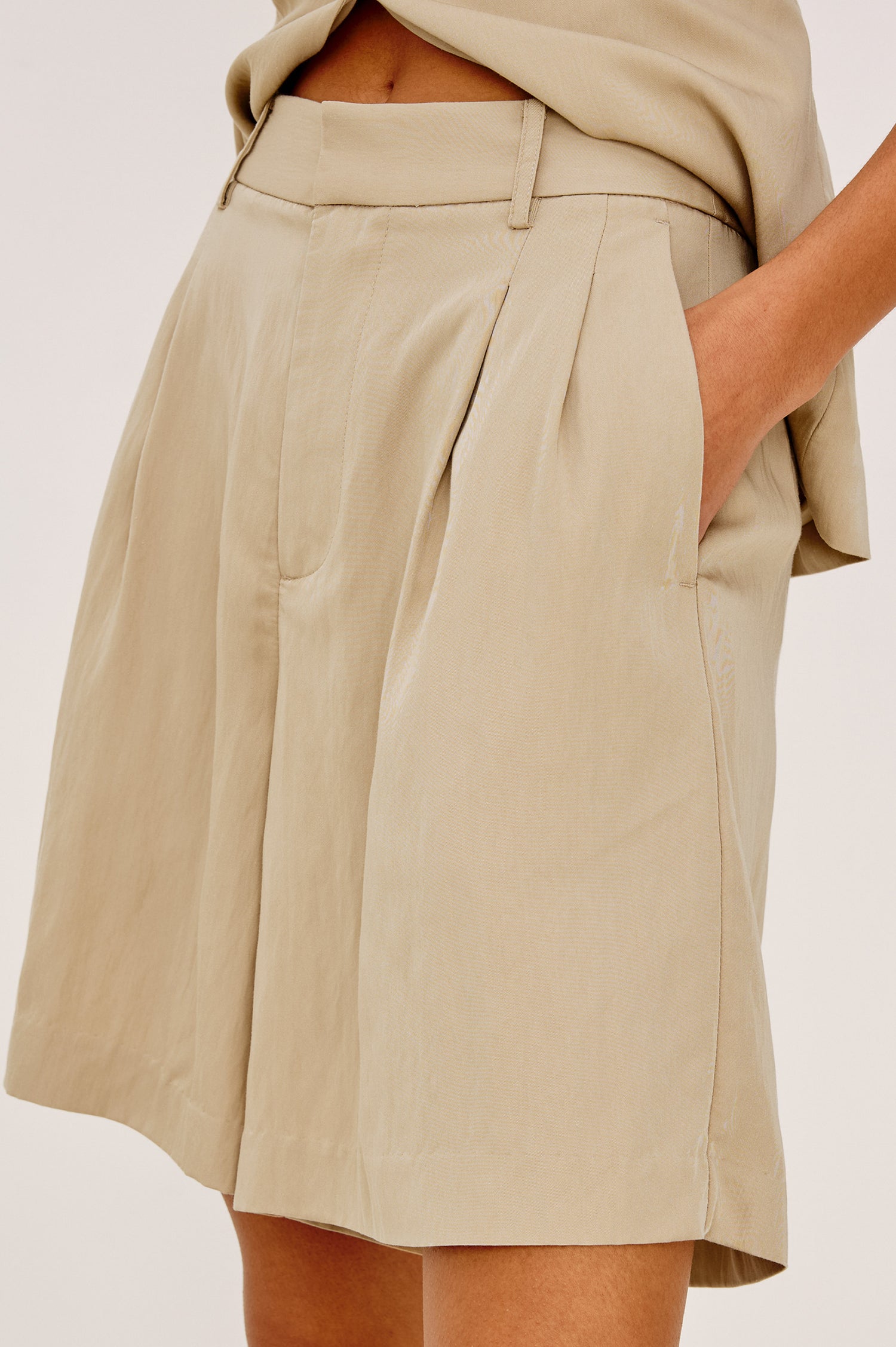 Zamora High-Waisted Bermuda Short in Linen Viscose With Front Pleats and Side Pockets in Almond Colorway - Lower Body Side Close Up View Featured on Model