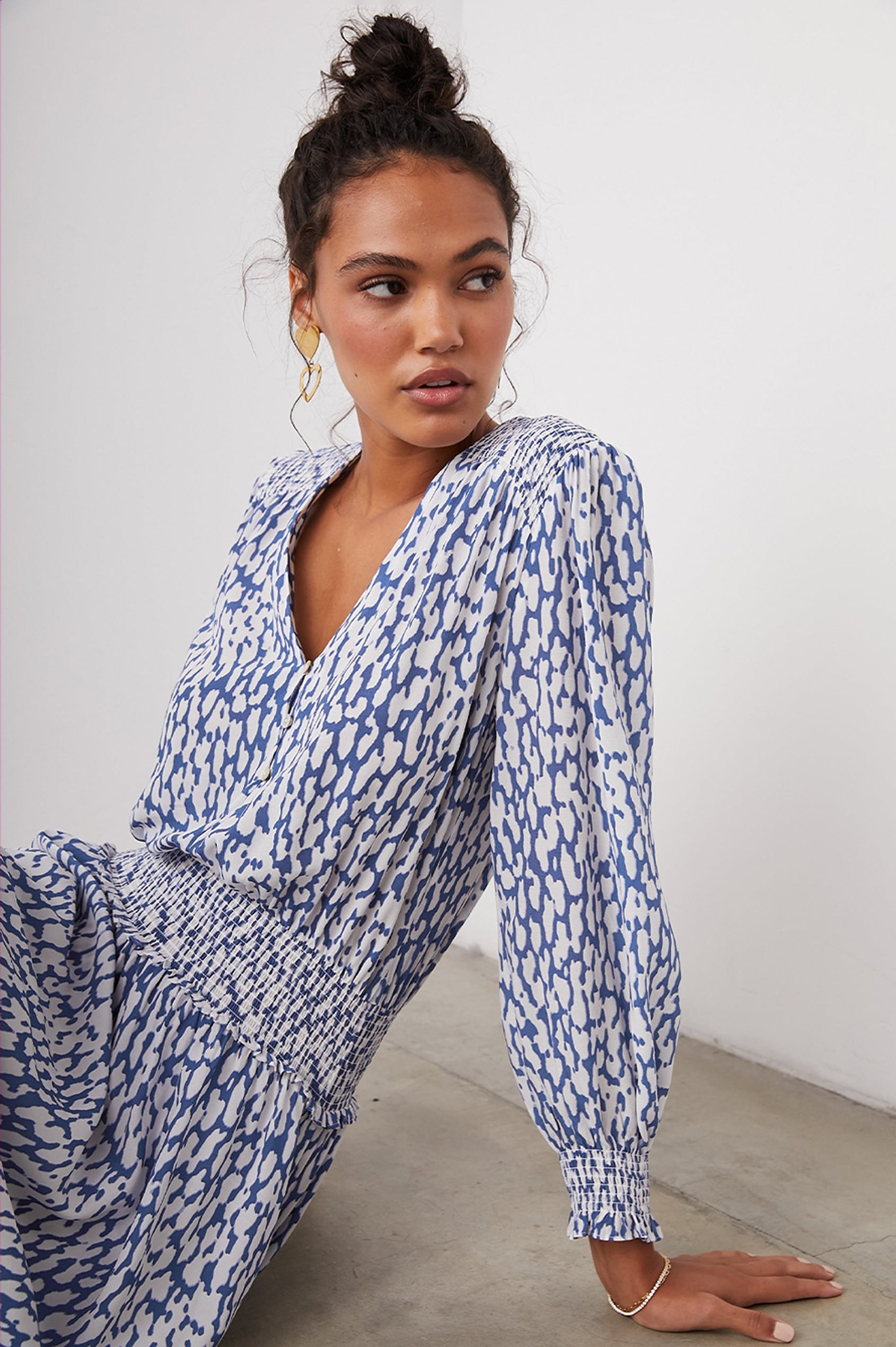 Zana Long-Sleeve Mini Dress with a V Neck, Smocked Cuffs and Waist, and Buttons Down the Bodice in Cobalt Static Leopard Colorway, a White and Cobalt Spotted Print - Front View Featured on Seated Model