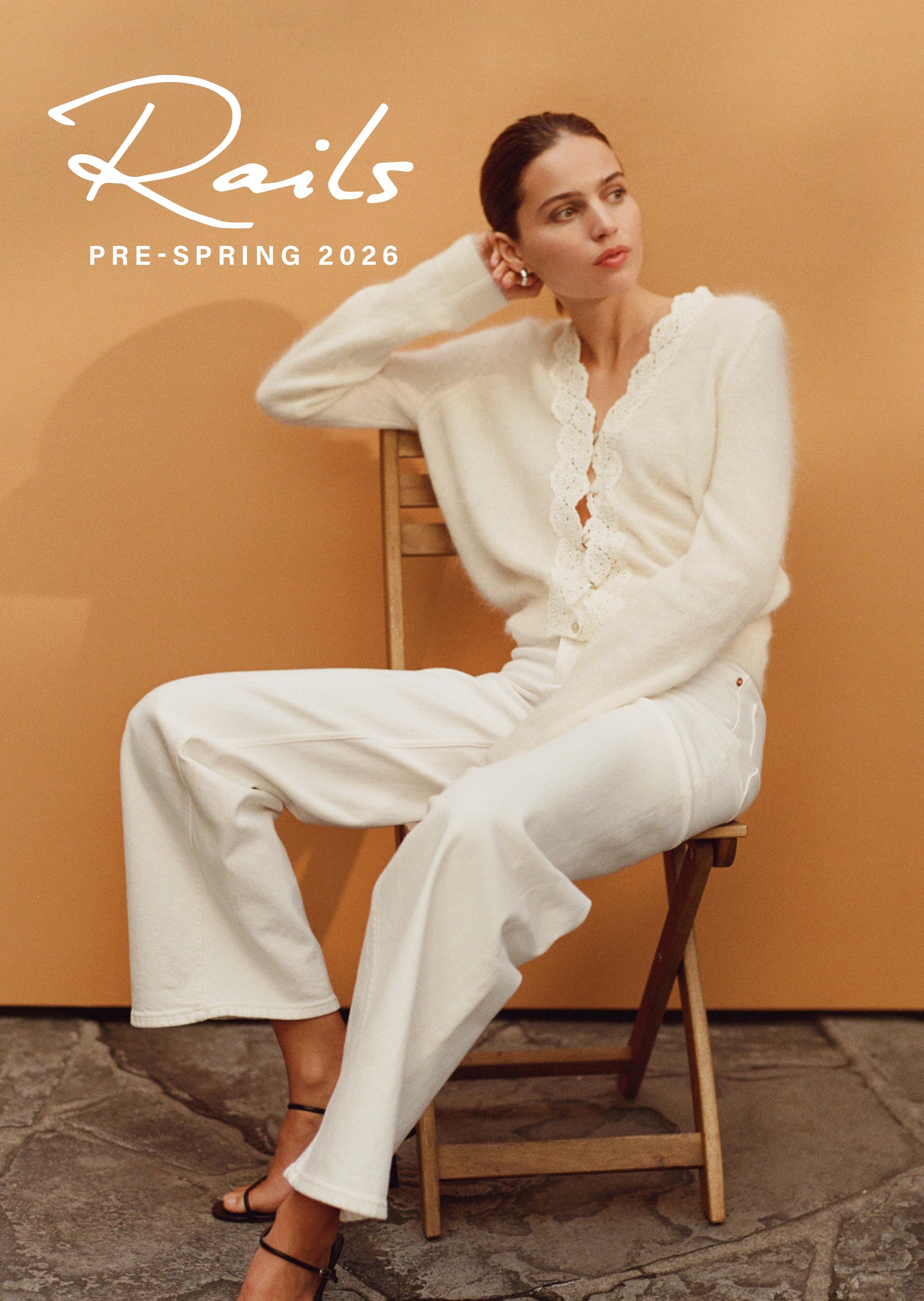 Woman in a white outfit sitting on a chair with 'Rails' branding above her.