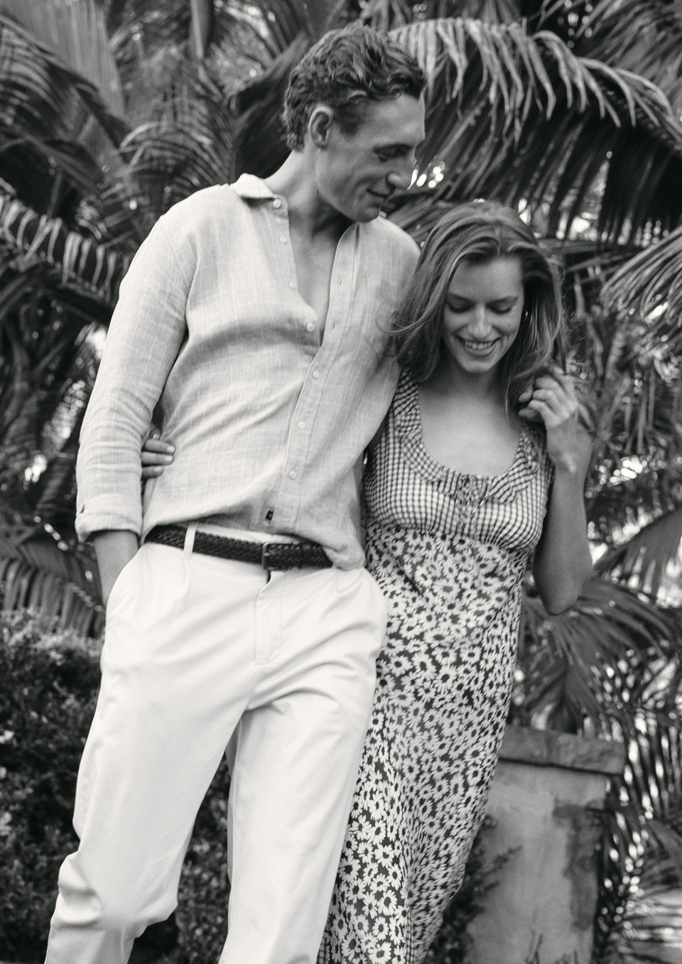 Black and white photo of a couple standing together with tropical plants in the background