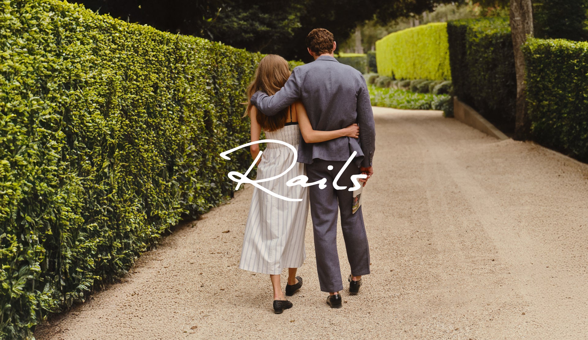 Couple walking arm-in-arm on a path with 'Rails' logo overlay