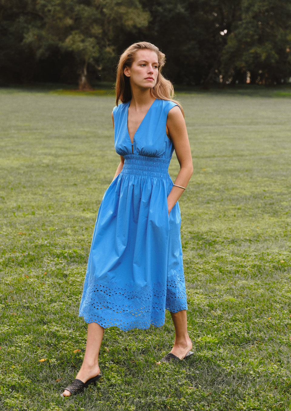 Woman in a blue dress standing in a grassy field