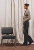 Mandy Sweater in Cashmere-Cotton-Wool Blend Knit Front Buttons, Long Sleeves, Classic Slightly Cropped Fit, and Ribbed Ruffle Trim in Heather Latte Colorway - Full Body View Featured on Model Posing with Chair (Video).
